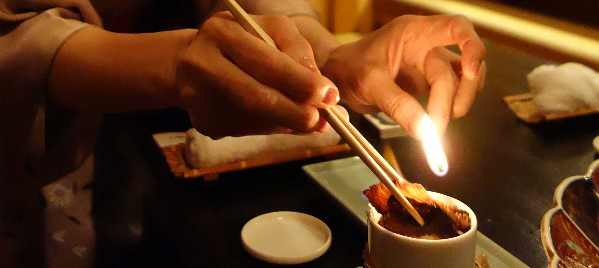 Хозяйка ресторанчика опаляет на огне плавник рыбы фугу и опускает его в плошку с сакэ, чтобы приготовить фугу-хикэ-дзакэ